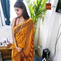 Mustard yellow Maheshwari saree with intricate floral and geometric Bagh print paired with a maroon blouse.
