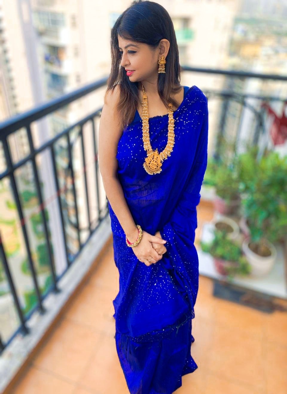 Royal blue Matka silk saree with sequin detailing worn with matching sleeveless blouse and gold jewelry.