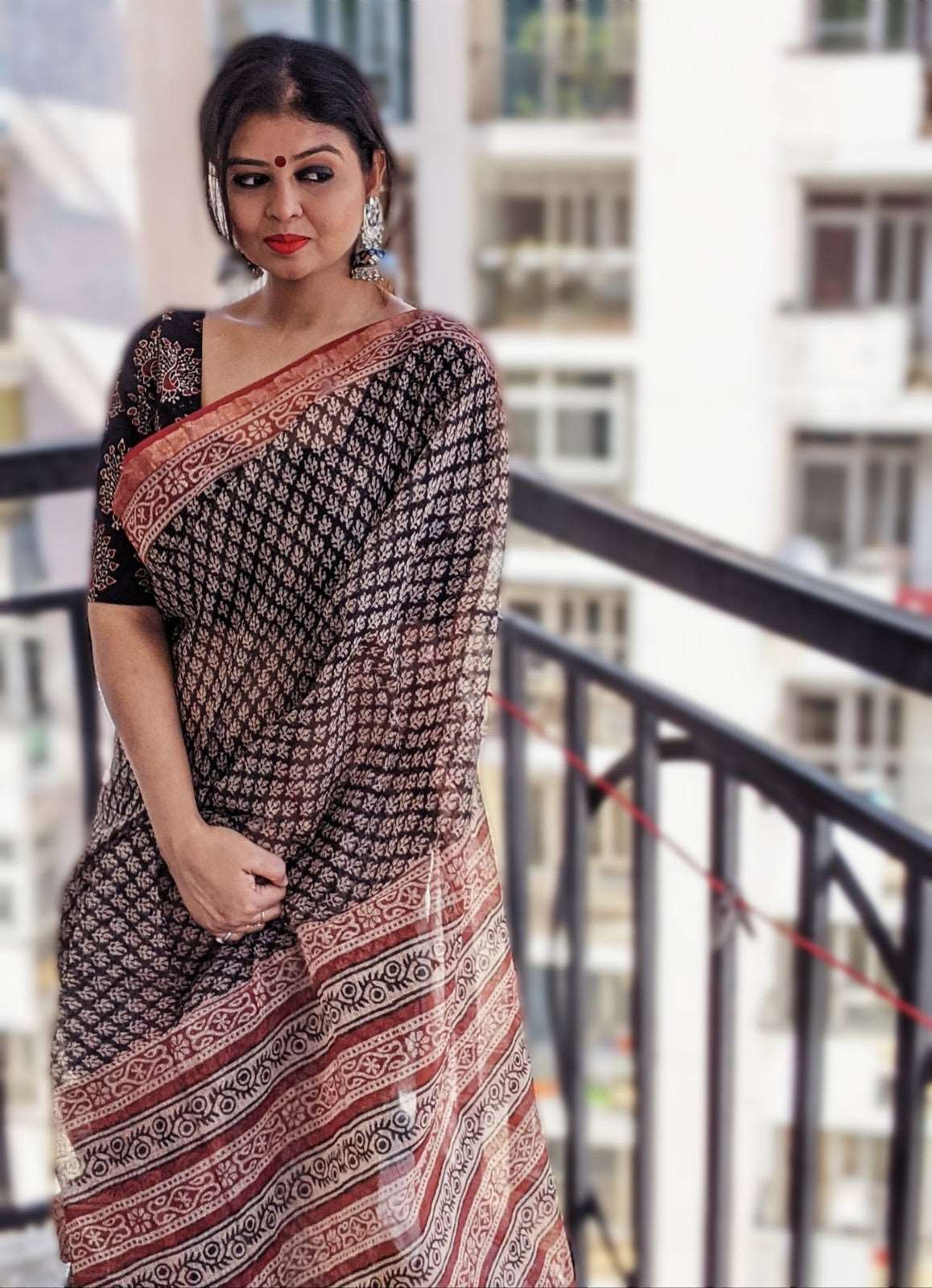 Black and rust Kota Doriya saree with geometric and floral motifs, paired with black blouse.