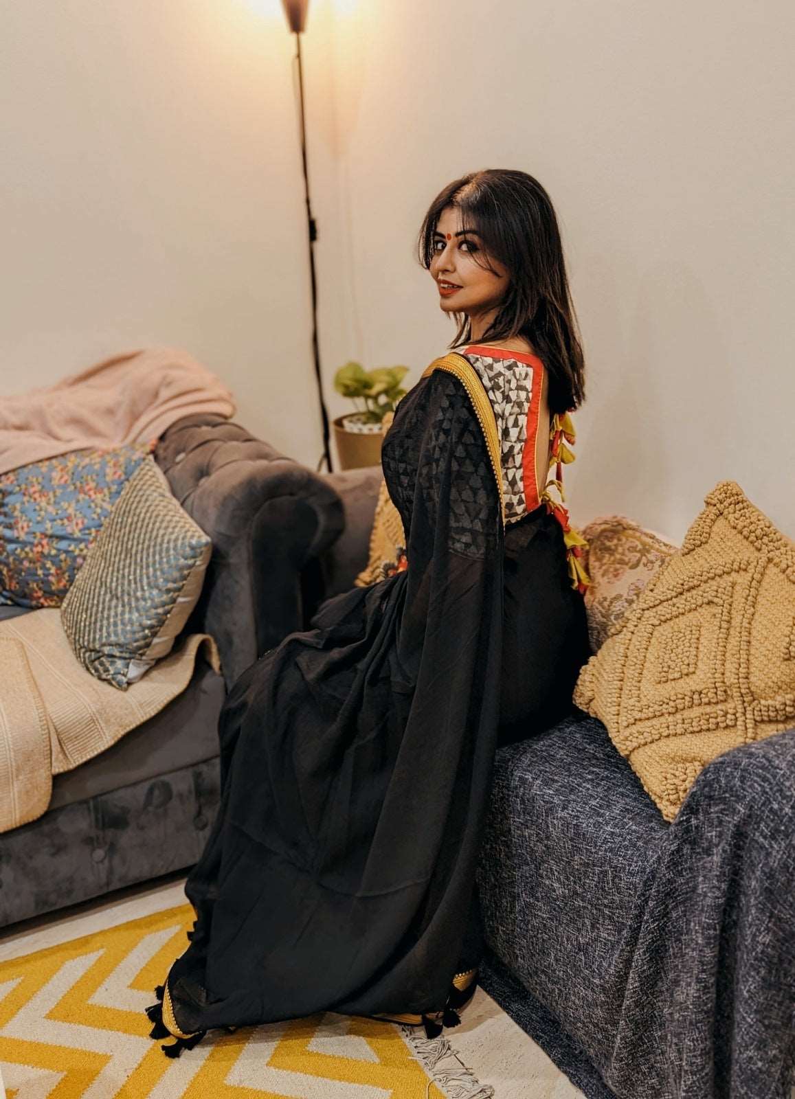 Black Mul saree with intricate orange and gold embroidered blouse, styled with loose hair and minimal makeup.