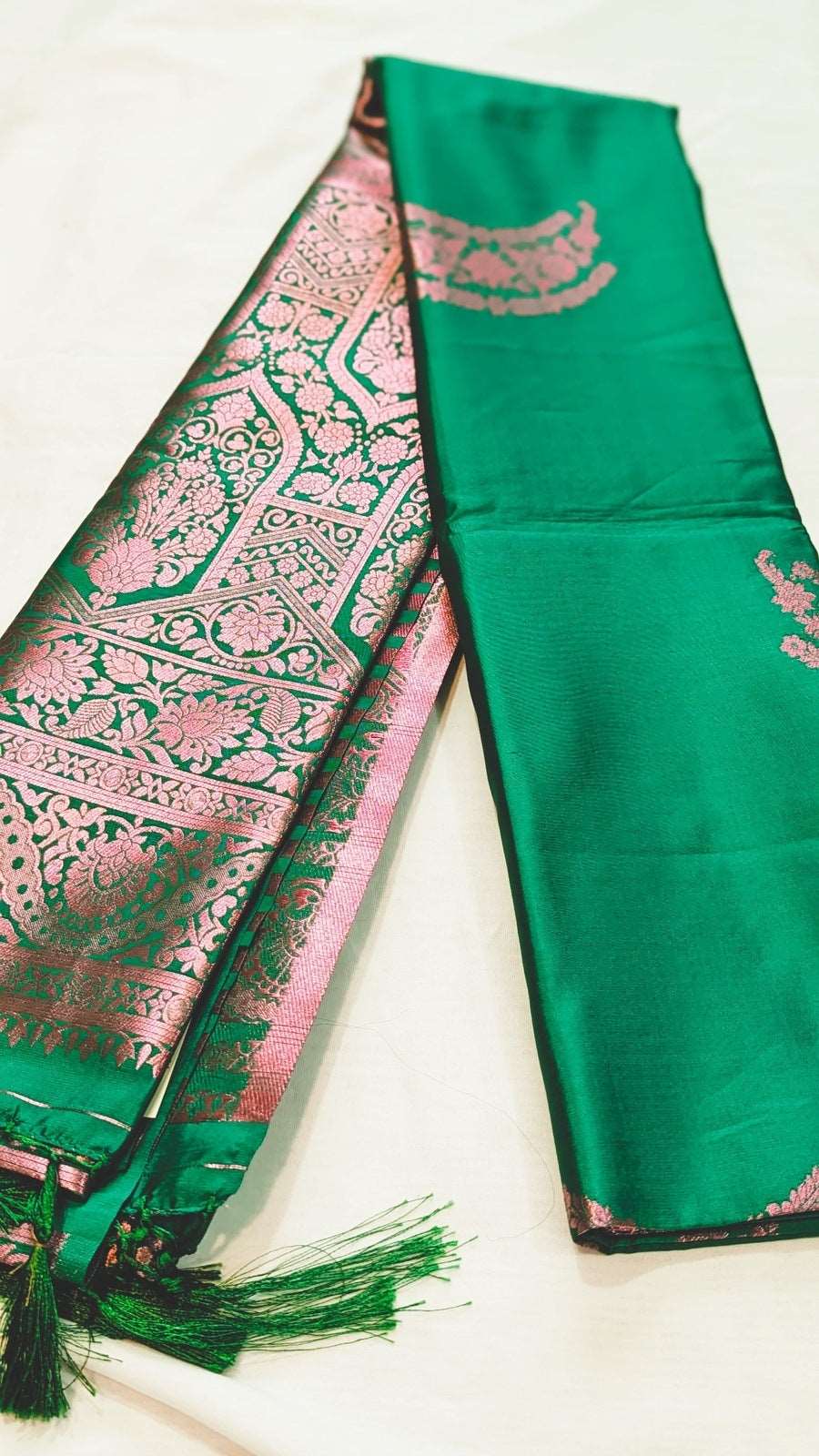 Emerald green Kanchi silk saree with intricate pink and gold zari border and pallu detailing.