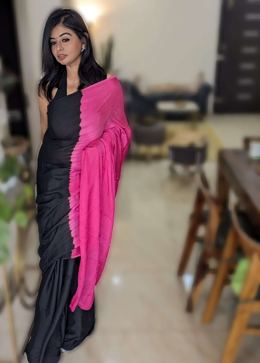 Black sleeveless blouse paired with elegant black and magenta tie-dye viscose modal silk saree with ruffled magenta pallu.