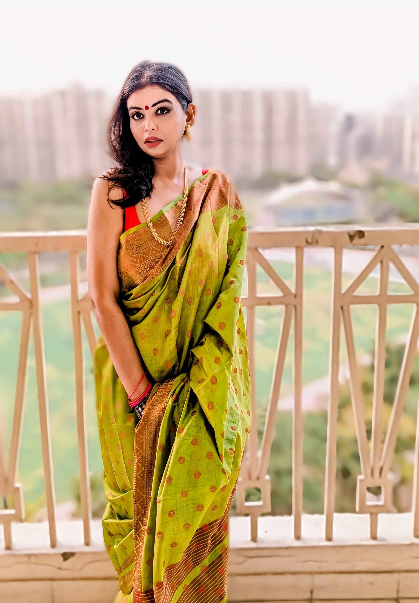 Lime green Banarasi silk saree with tomato red buta patterns, worn with a matching blouse, styled with traditional jewelry.