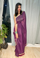 Deep purple mul zari saree with golden border and tassel detailing, styled with green bangles and red lipstick.