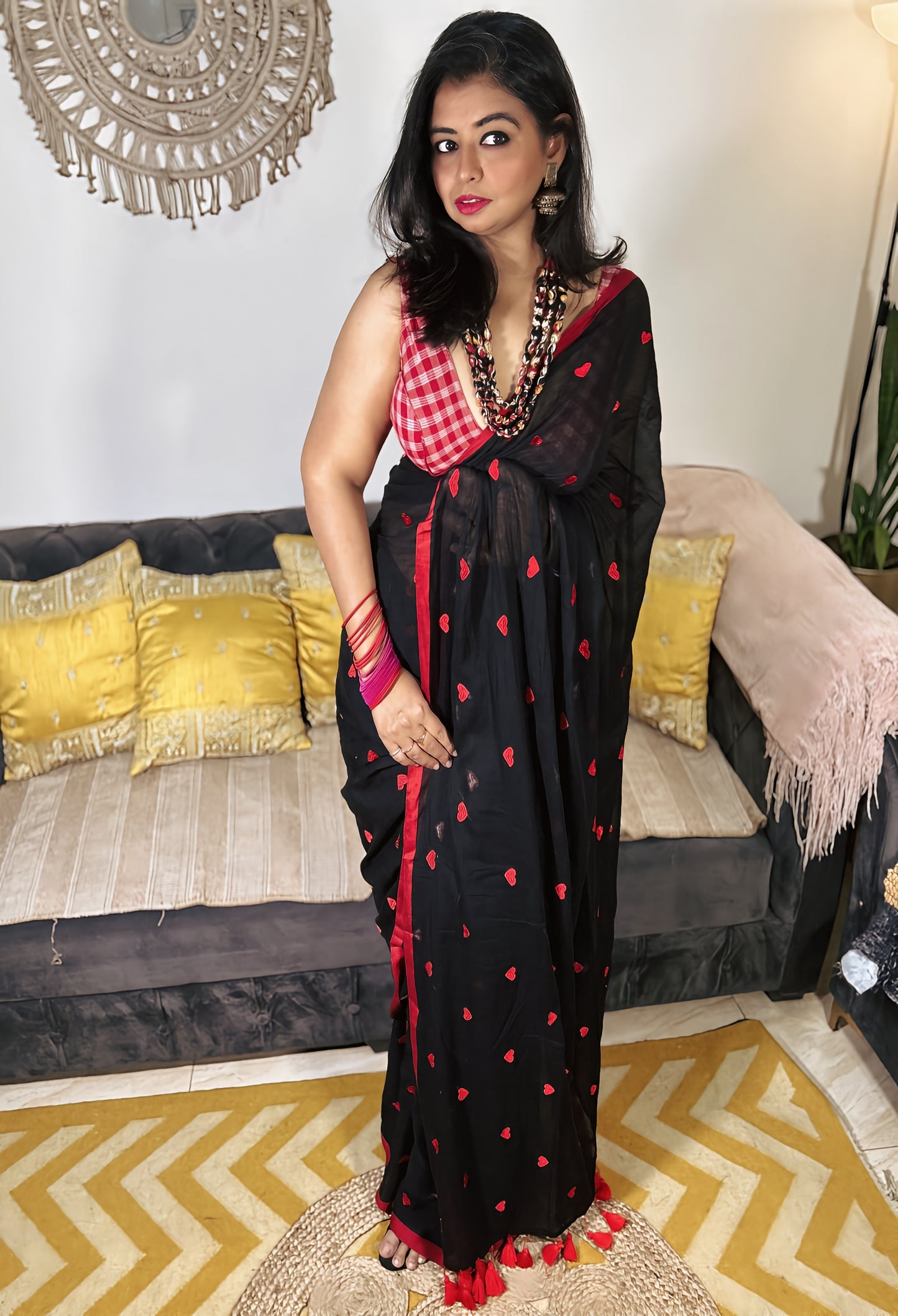 Black Bengal cotton saree with red love knot motifs and border, paired with red blouse and jewelry.
