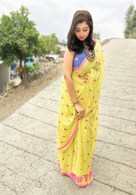 Yellow handloom Bengal cotton saree with pink border and floral motifs, worn with blue blouse.