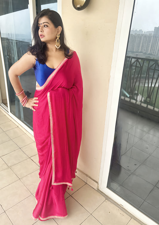 Bright rani modal silk saree with deep blue blouse and delicate gold signature border.