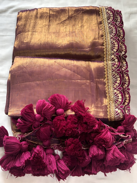 Mauve soft tissue saree with golden sheen and intricate maroon scalloped border with tassels.