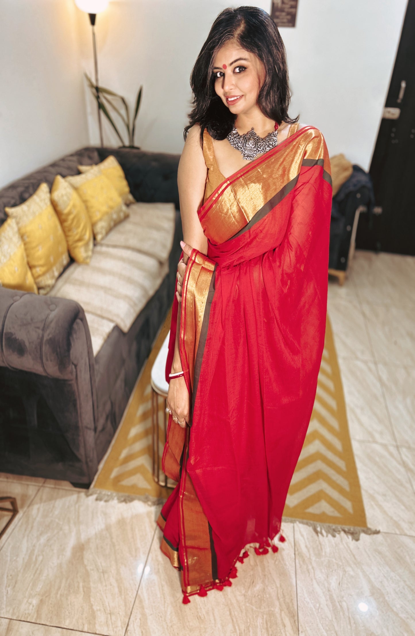 Red mul saree with gold border and delicate gold motifs, draped elegantly on model.
