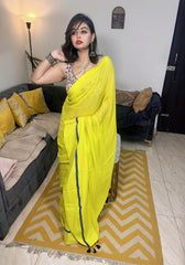 Bright yellow saree with navy blue border, paired with a printed blouse, draped elegantly.