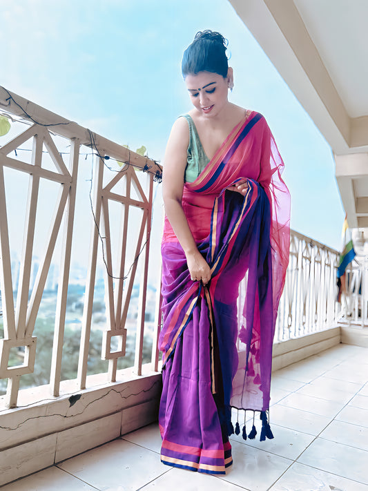 Magenta and purple pure handloom mul saree with gold border and tassels, draped on woman.