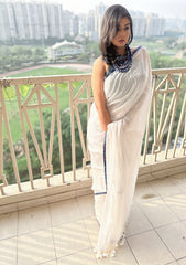 White Mul saree with subtle texture and Ajrakh indigo geometric border paired with indigo blouse and statement necklace.