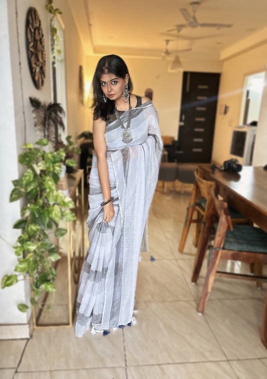 Woman wearing monochrome striped mul cotton saree with silver blouse in bright indoor setting.