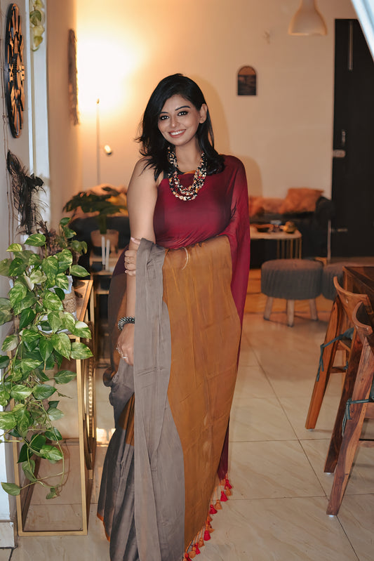 Handloom mul saree with mustard yellow body, maroon blouse, and gray pallu with red tassels.