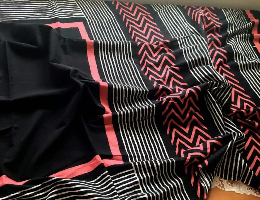 Black saree with pink and white geometric and striped patterns in mul fabric.