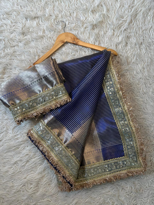 Royal blue Banarasi tissue saree with gold waterfall lace border and intricate silver zari patterns.