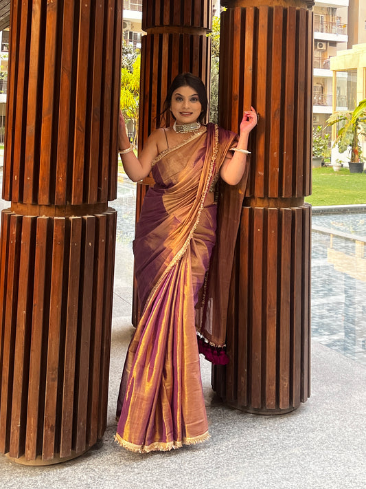 Copper purple tissue saree with gold zari border and elegant drape, worn with matching blouse.