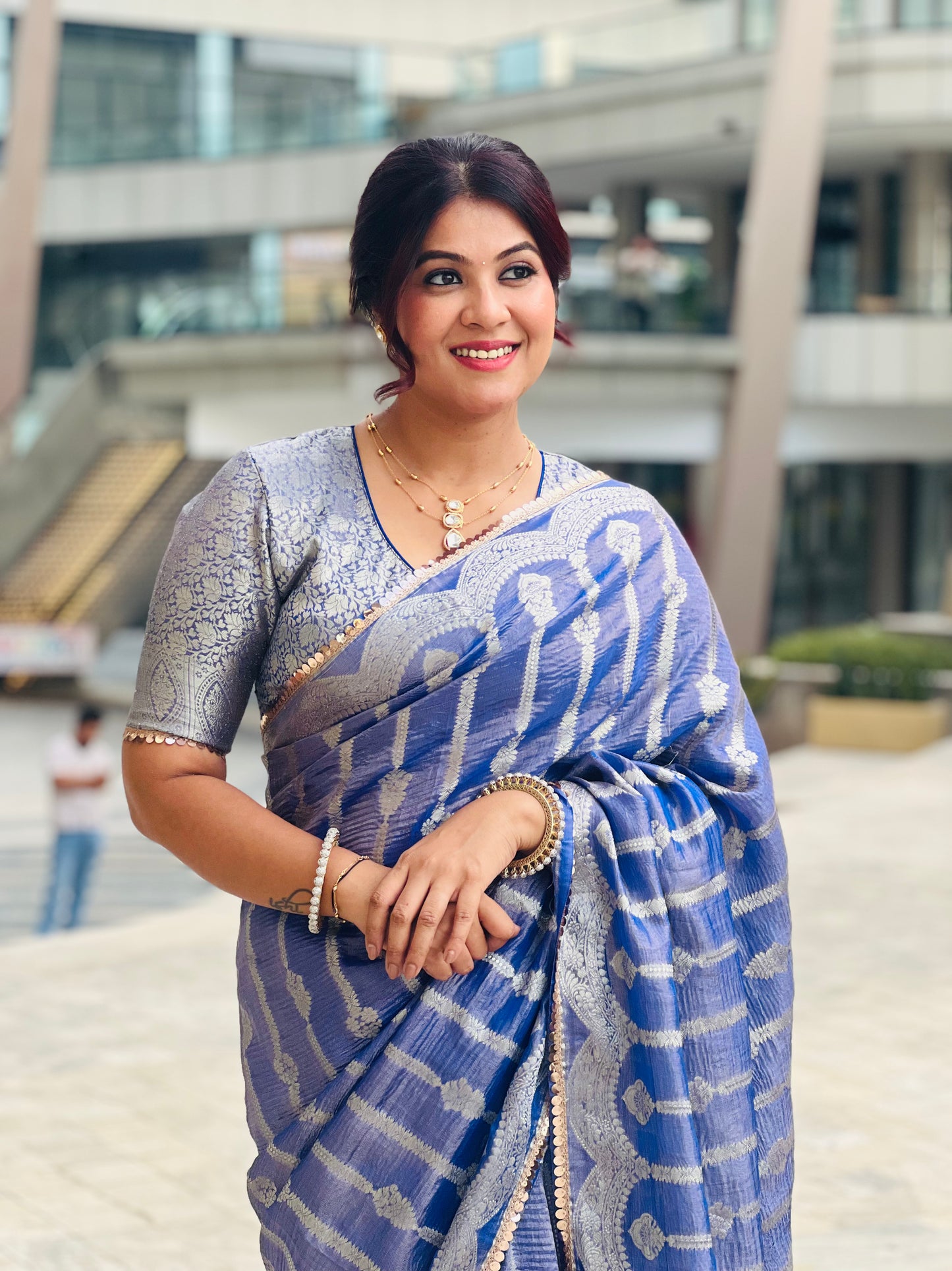 Blue crushed tissue saree with silver zigzag pattern, paired with silver sequin blouse and gold jewelry.