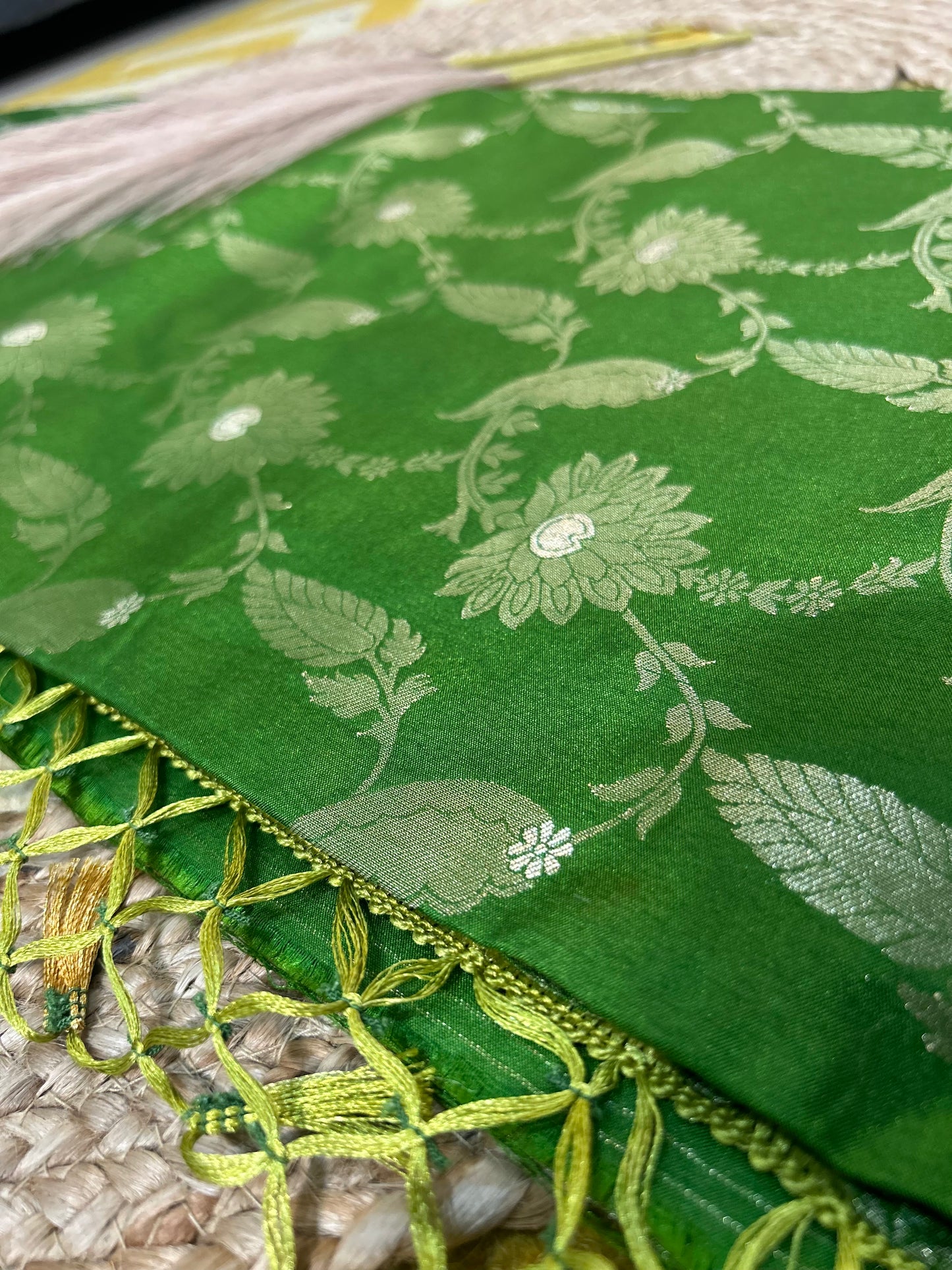 Green Banarasi silk saree with intricate silver floral motifs and detailed leaf patterns, featuring green and gold woven.
