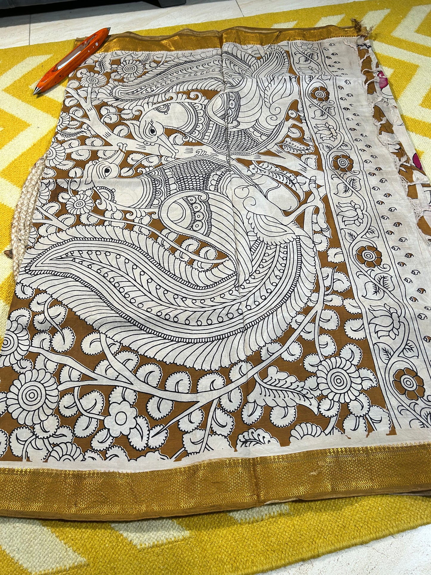 Offwhite Kalamkari saree with intricate brown floral and bird motifs, gold border detailing.