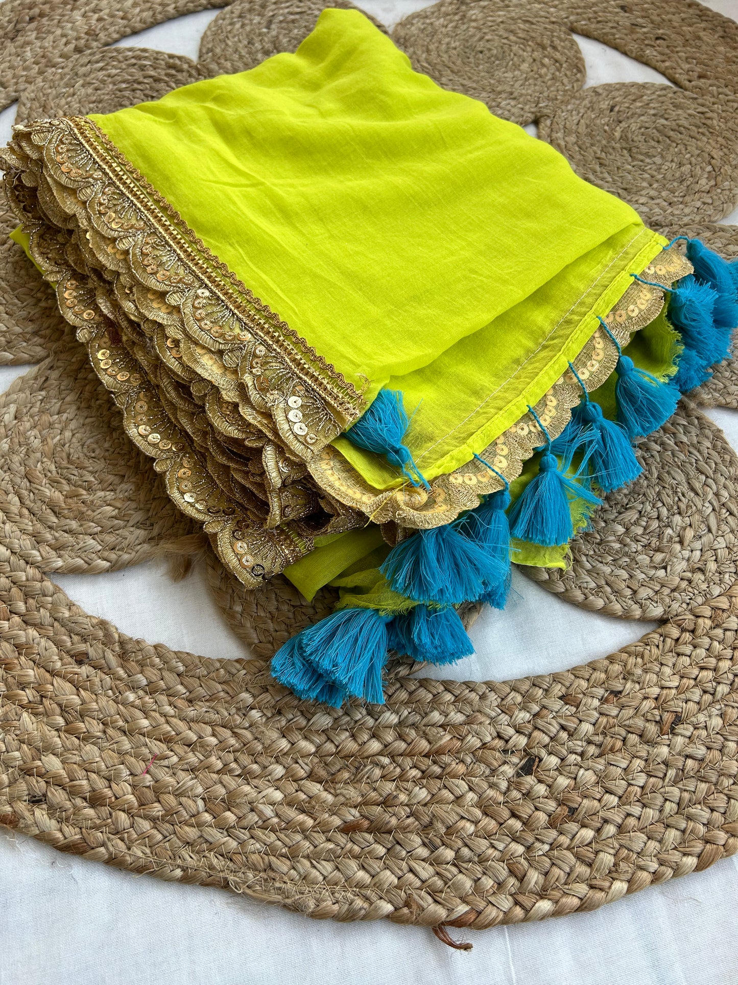 Bright neon yellow handloom mul saree with intricate gold border and blue tassels on pallu end.