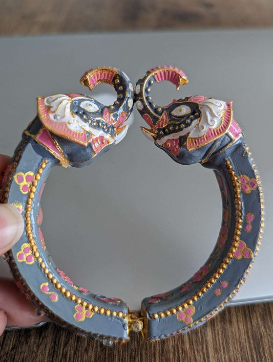 Grey bangles with intricate pink and gold Kundan-style elephant head designs on each end.