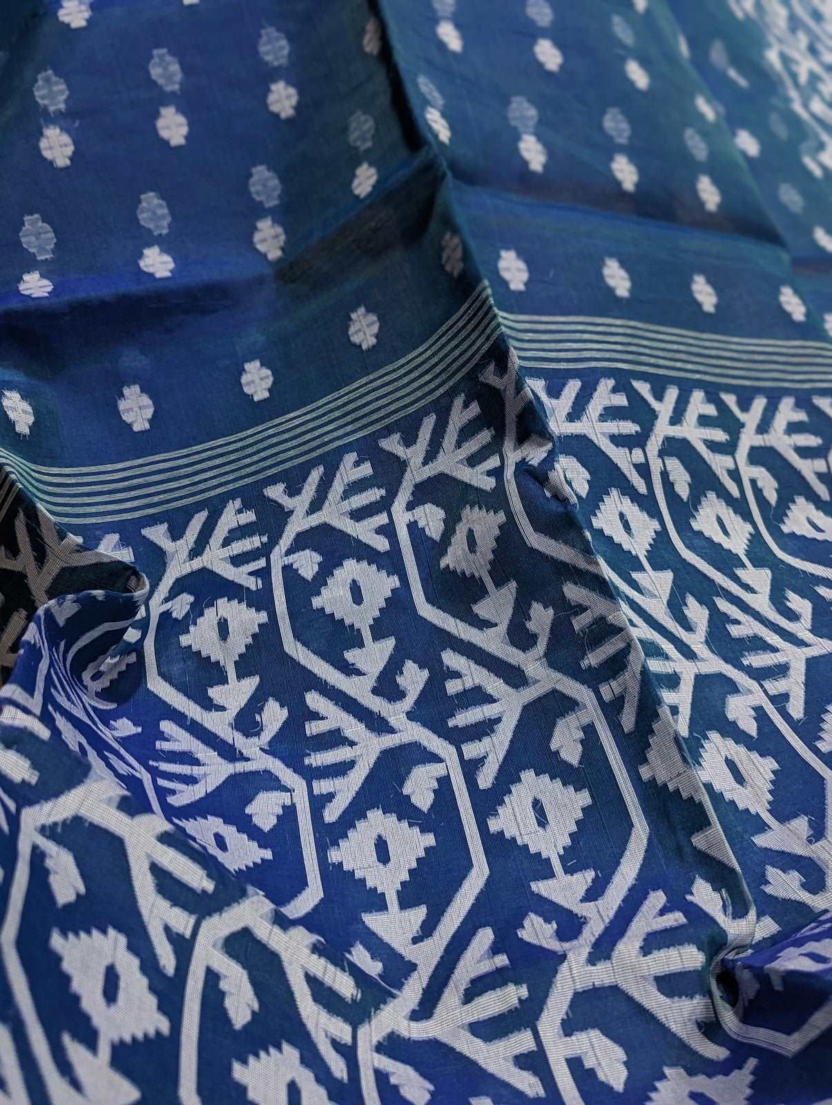 Navy blue cotton silk fabric with white floral Dhakai Jamdani patterns and intricate vine border designs.