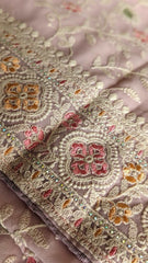 Soft blush georgette saree with intricate floral embroidery in gold, pink, and orange threads.