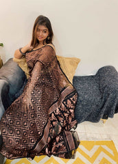 Brown and black Bengal Loom saree with geometric Dhakai Jamdani patterns worn by seated woman.