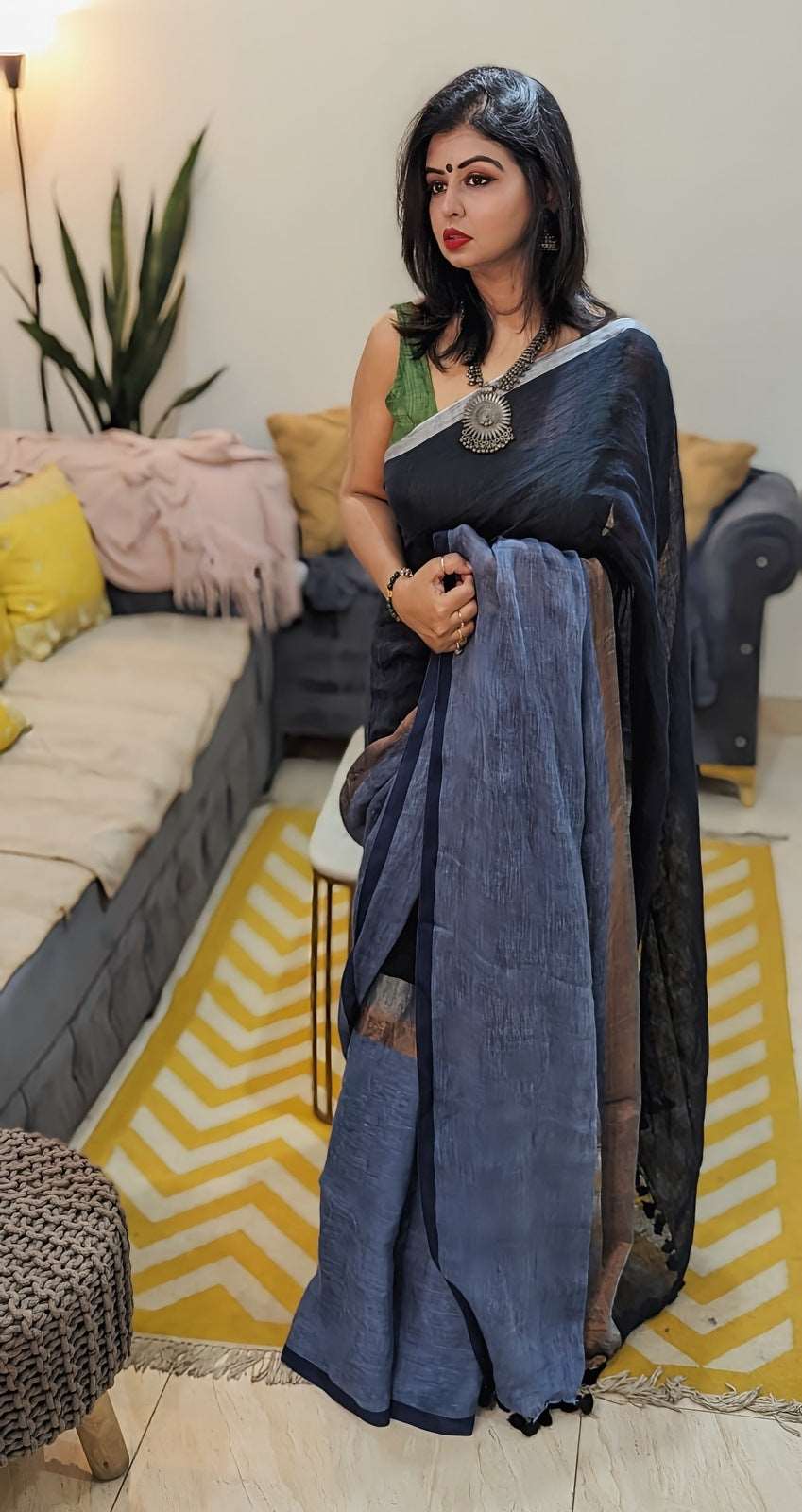Indigo blue linen saree with black border and silver detailing worn with matching black blouse.