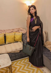 Black tissue saree with magenta pompom border, paired with purple blouse and gold jewelry.