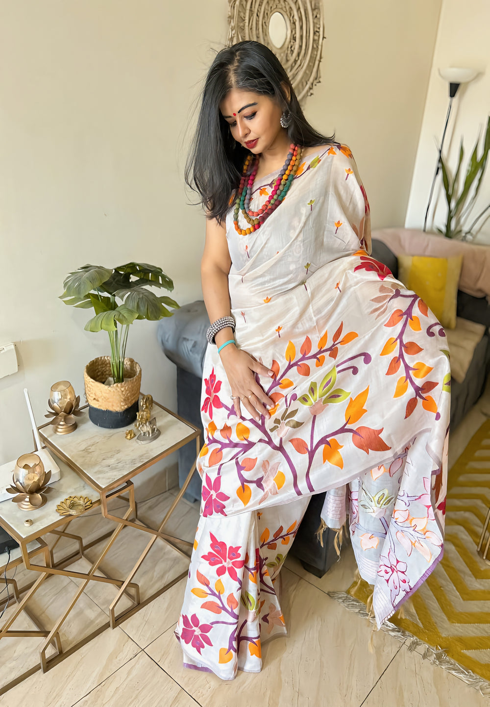 Ivory silk Jamdani saree with colorful floral motifs worn with red and orange layered necklace.