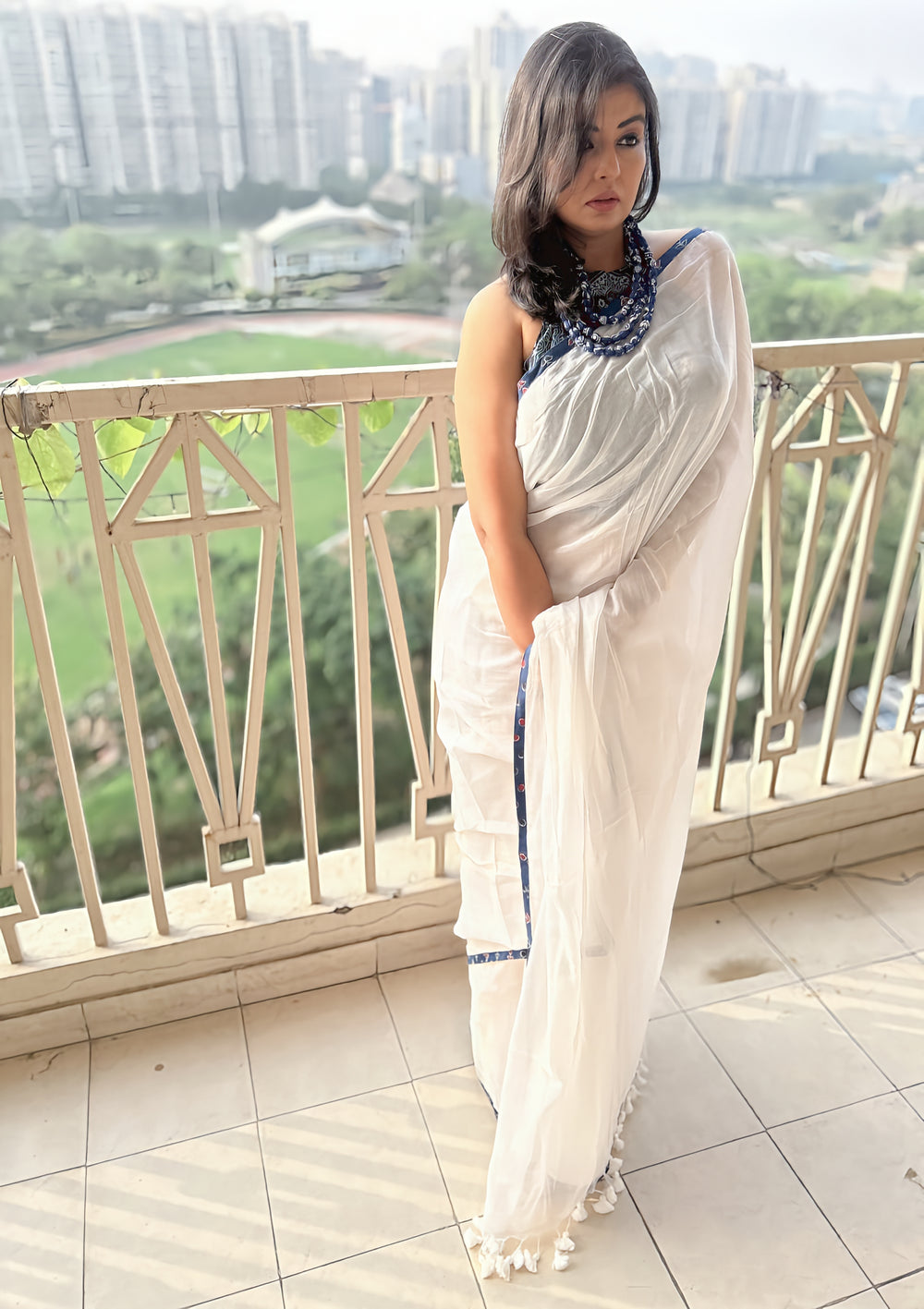White Mul saree with subtle texture and Ajrakh indigo geometric border paired with indigo blouse and statement necklace.