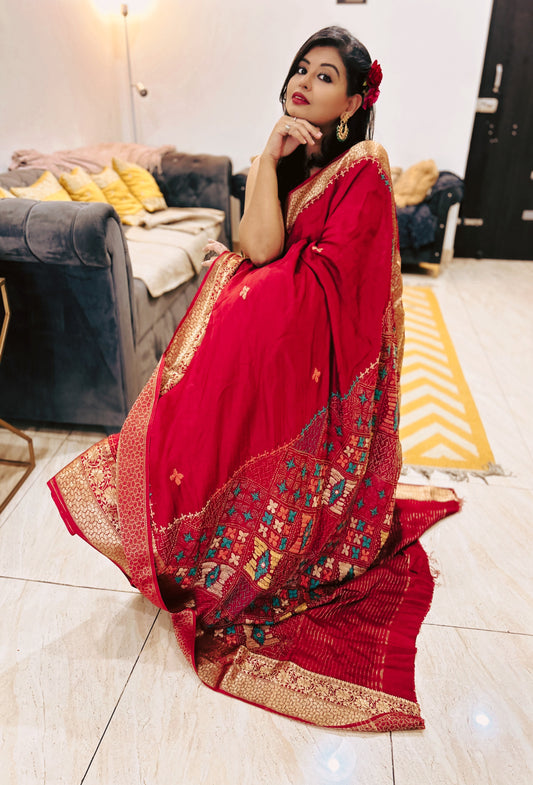 Deep blood red Pure Dola Silk Lambani saree with intricate multicolor geometric border and gold detailing.